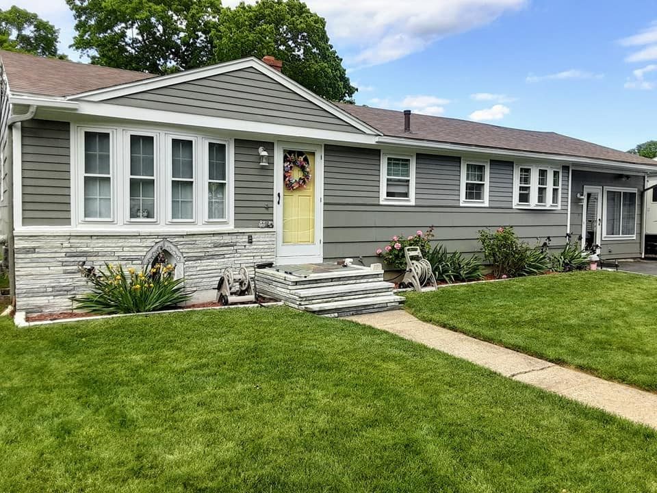 Gray ranch home exterior with white trim and a yellow front door painted by Genesis Painting