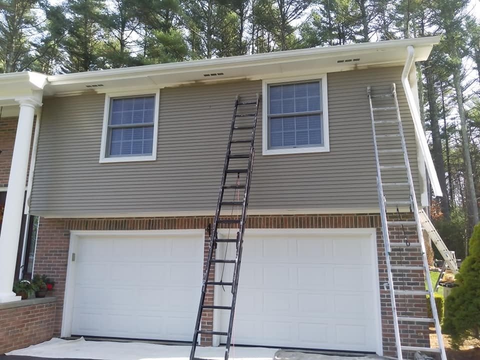 Ladders set up on a two-story home exterior by Genesis Painting